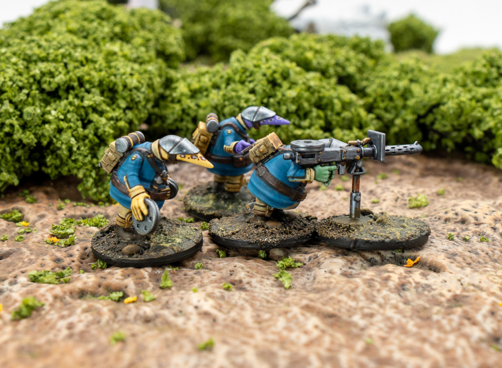Coftyran Quar heavy machine‑gun team operating an M3B HMG on a scenic terrain base, with three blue‑uniformed Quar coordinating the weapon.